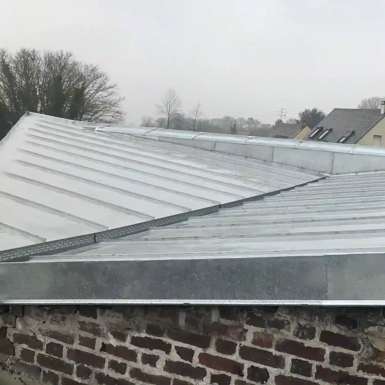 Toiture en zinc à joint debout posée au-dessus d’un mur en brique